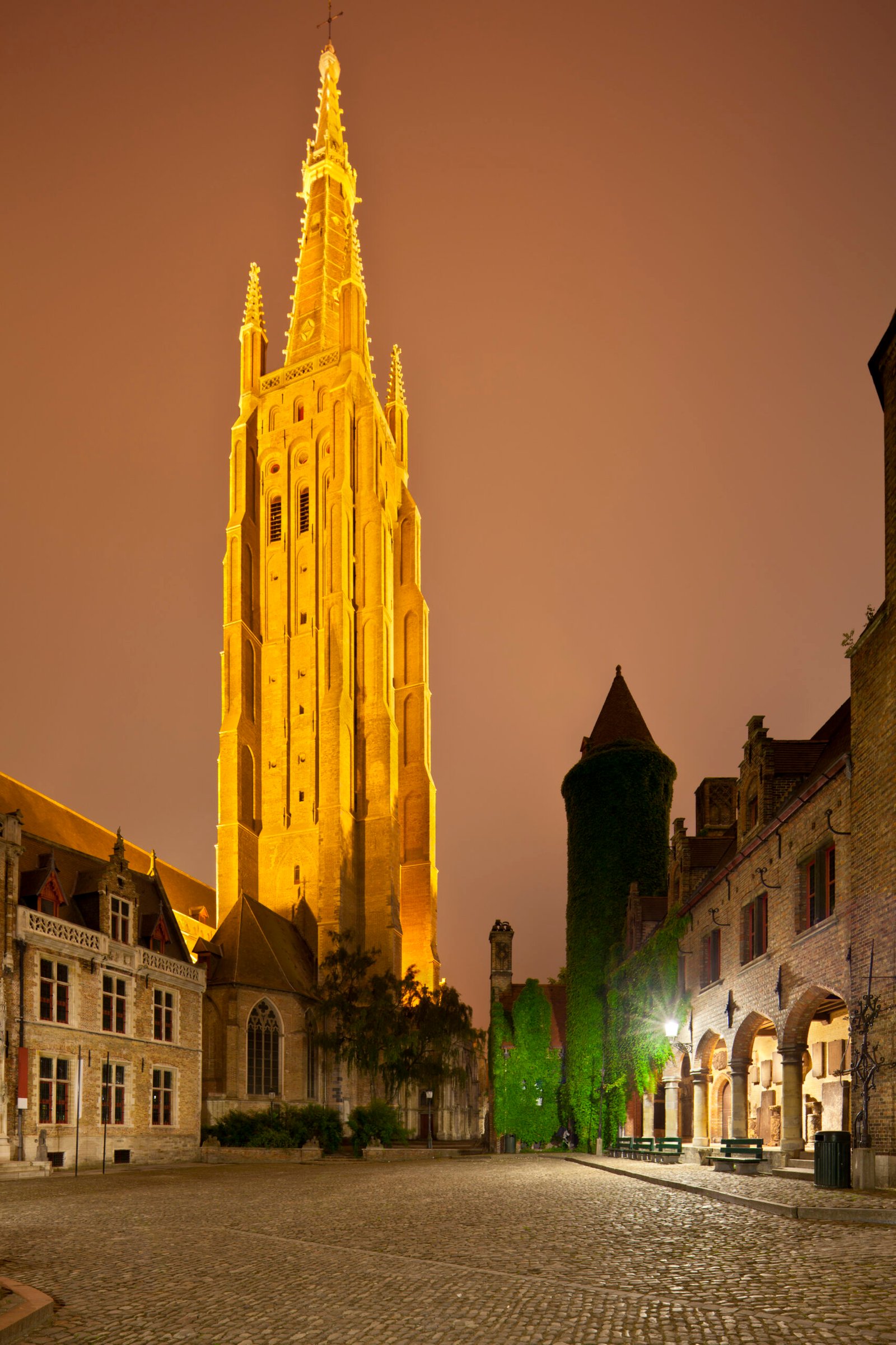 View to the illuminated tower of the Church Of Our Lady in Bruges at night with the Gruuthuse Museum buildings as foreground. Perspective corrected via lens shift.